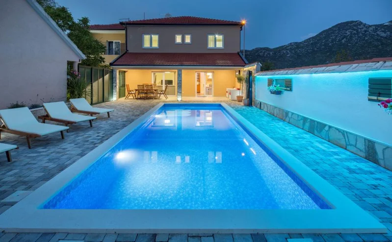 Private heated pool with sun loungers seen from covered pergola at Villa Žarka in Zavojane